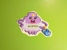 a cross stitch sticker with a purple monster holding a blue object