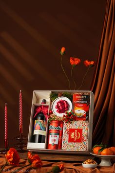 an open gift box with candles, flowers and condiments on a brown table cloth