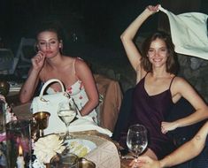 two women sitting at a table with wine glasses and napkins in front of them