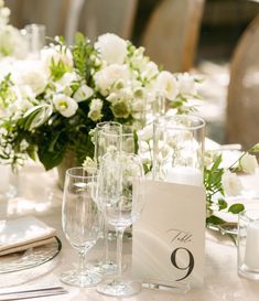 the table is set with white flowers and silverware