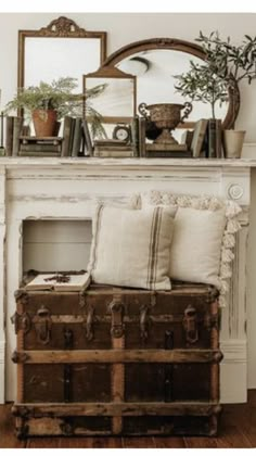 an old trunk is sitting in front of a mirror and potted plant on the mantle