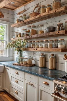 a kitchen filled with lots of open shelving and wooden shelves next to a window