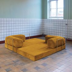 a yellow couch sitting on top of a tiled floor