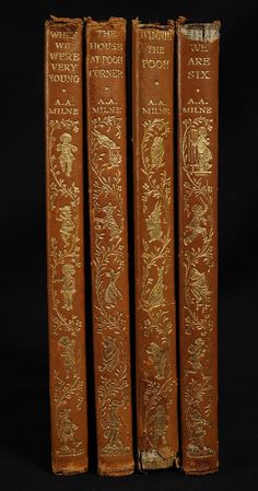 three antique books with gold embosishments on brown leather covers, lined up against a black background