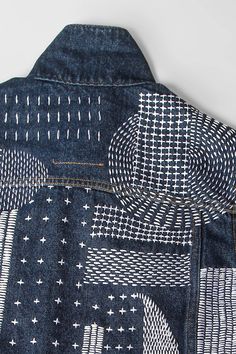 the back of a jean jacket with white and blue designs on it, showing an open pocket