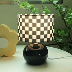 a black and white lamp sitting on top of a table next to a potted plant