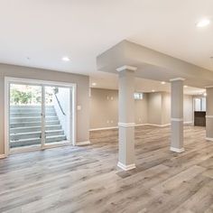 an empty living room with wood flooring and white pillars in the middle of it