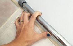 a person is using a hand to push the curtain rod up against the wall and down