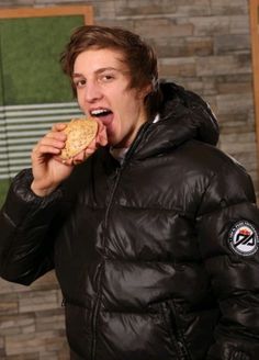 a man in a black jacket eating a cookie