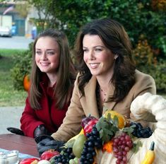 two women sitting at a table full of fruit