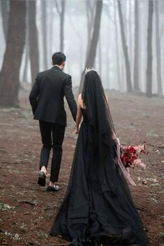 a bride and groom walking through the woods