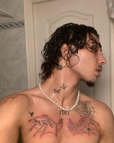 a man with tattoos on his chest standing in front of a mirror