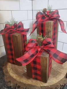 three wooden blocks with red and black plaid ribbon tied around the ends, sitting on top of a tree stump