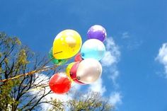 several balloons floating in the air near trees