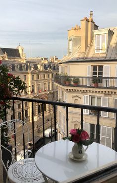 a table and chairs on a balcony overlooking the cityscape in paris, france