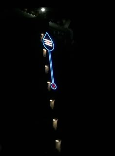 there is a lit up sign on the side of a building that has candles in front of it