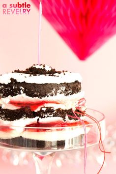 a cake with two candles on top of it sitting on a glass platter in front of a pink background