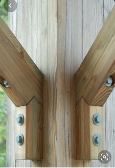 two wooden brackets are attached to the side of a wood structure with metal rivets