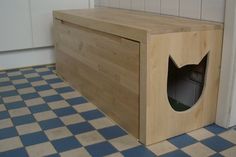 a wooden box with a hole in it on the floor next to a tiled wall