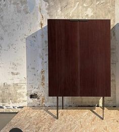 a large wooden cabinet sitting on top of a cement floor next to a white wall