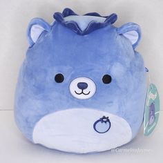 a blue stuffed animal with black eyes and nose ring on it's head, sitting in front of a white background