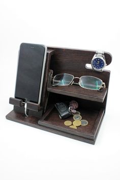 a cell phone and some glasses in a wooden case with coins on the bottom shelf