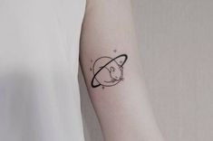 a small cat tattoo on the left forearm and right arm, with an outline of saturn in black ink