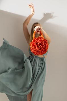 a woman in a green dress is holding a handbag with a rose on it