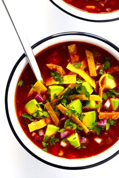 two bowls of soup with avocado, red onion and tortilla chips