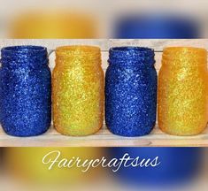 four blue and yellow glittered jars lined up on a wooden surface