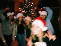 a group of people wearing christmas hats posing for a photo in front of a christmas tree