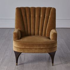 a brown chair sitting on top of a hard wood floor next to a white wall