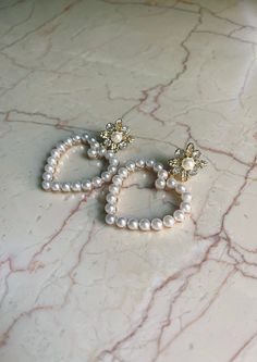 "🫶🏼 We've officially launched our new heart collection and we're obsessed. The Pearl Heart Statement Earrings are a perfect way to embellish an otherwise simple, subtle ensemble. We think these will be the perfect earring to be the \"it\" factor of every chic, classic look.  Pair with our padded matador for a Blair Waldorf aesthetic.  Materials: Stainless Steel  All accessories handmade in Florida.  *International and domestic expedited shipping available upon checkout. *Earrings are for pierc Heart-shaped Pearl Earrings For Valentine's Day, White Heart-shaped Pearl Earrings For Valentine's Day, Heart Charm Pearl Earrings As A Gift, Heart Charm Pearl Earrings For Gift, Heart-shaped Pearl Drop Earrings For Party, Heart Shaped Pearl Drop Earrings For Valentine's Day, Heart-shaped Pearl Earrings For Valentine's Day Anniversary, Heart-shaped Pearl Earrings For Anniversary On Valentine's Day, Heart-shaped Pearl Earrings For Anniversary And Valentine's Day