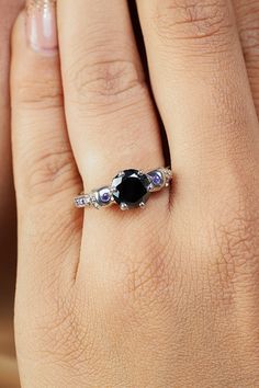 a woman's hand with a black and white diamond ring on her left hand