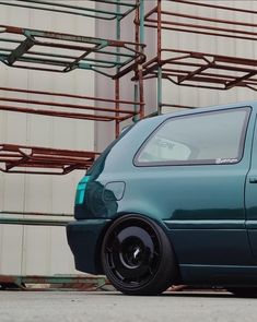 a blue car parked in front of a building with scaffolding on the side