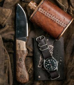 a knife, watch and some other items are laid out on a piece of cloth