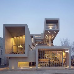 a modern house with stairs leading up to the upper floor and second story, in front of two buildings at dusk