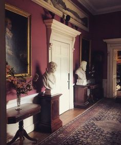 an ornate hallway with busturines and paintings on the walls, along with a bench