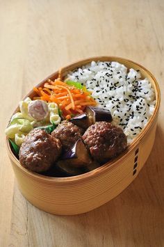 a wooden bowl filled with rice, meatballs and veggies