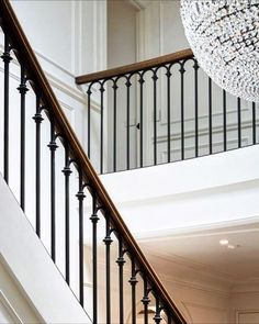 a chandelier hanging from the side of a stair case next to a banister