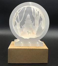 a paper cut out of a forest with trees and a dog in the center on a wooden base