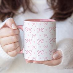 a woman holding a pink coffee mug with hearts on it