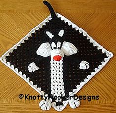 a black and white crocheted square with a red nose