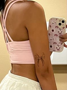 a woman with a tattoo on her left arm holding a cell phone in her right hand