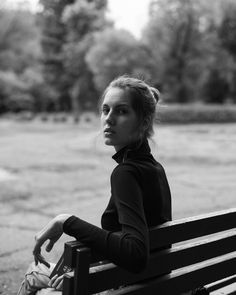 a black and white photo of a woman sitting on a bench