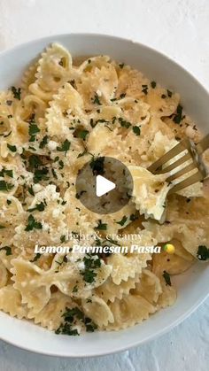 a white bowl filled with pasta covered in parmesan cheese and garnished with parsley