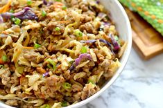 a white bowl filled with coleslaw on top of a table next to a cutting board