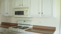 a white stove top oven sitting inside of a kitchen next to wooden counter tops and white cabinets