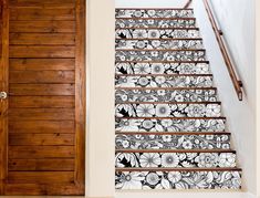 a stair case with flowers on it next to a wooden door and some stairs in the background