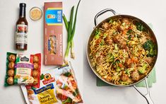 a pan filled with noodles, meatballs and veggies on top of a table